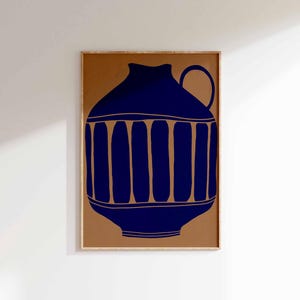 May include: A framed wall art print featuring a dark blue graphic illustration of a ceramic pitcher with a rounded body, a small handle, and vertical stripe details set against a solid, muted tan background within a light wood frame.