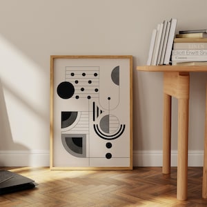 Könnte beinhalten: Ein gerahmter Schwarzweiß-Druck mit geometrischer abstrakter Kunst auf hellbeigefarbenem Hintergrund. Der Druck zeigt Kreise, Linien und Halbkreise.