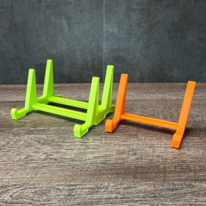 May include: Three picture frames, two are green and one is orange. The frames are made of plastic and are designed to stand upright.