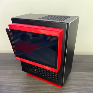 May include: A black computer case with a red screen and a black and silver front panel. The case has a mesh design on the front and a black antenna on the top.