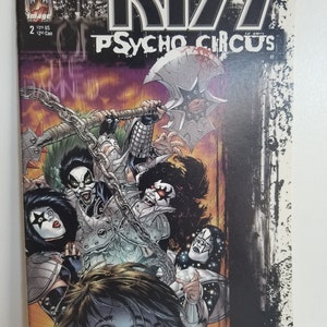 Peut inclure: Une couverture de bande dessinée mettant en scène le groupe KISS dans une illustration en noir et blanc. La couverture est intitulée "KISS Psycho Circus" et présente les membres du groupe dans une pose menaçante avec une hache et des chaînes. L'arrière-plan est un design sombre, granuleux et texturé.