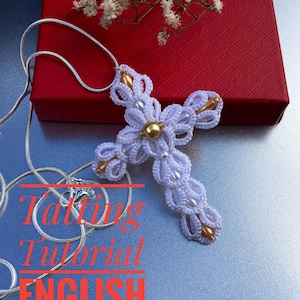 May include: White crocheted cross pendant with gold beads, hanging from a silver chain. The cross is on a gray surface with the text "Tatting Tutorial ENGLISH" in red.