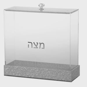 May include: Clear acrylic box with a textured silver base and a clear knob on the lid. The word "Maza" is etched on the front of the box. The box is rectangular and appears to be designed for storage.