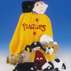 May include: A yellow drawstring bag with the word "PLAGUES" in red script, topped with two plush figures. Several plush figures in various shapes and colors, including black, red, and green, are scattered around the bag.