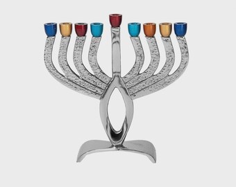 May include: A silver menorah with nine candle holders, each topped with a different colored cup: blue, gold, red, and teal. The base has a decorative, curved design. A religious item for Hanukkah.