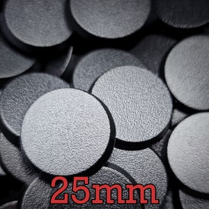 Puede incluir: Primer plano de una pila de bases redondas de plástico negro de 25 mm para figuras en miniatura. Las bases tienen una superficie texturizada.