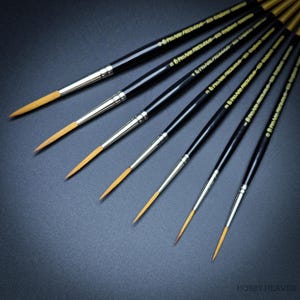 May include: A set of eight paint brushes with black handles and gold lettering that reads "Pro-Art Precision Series." The brushes have different sizes and are arranged in a fan shape.