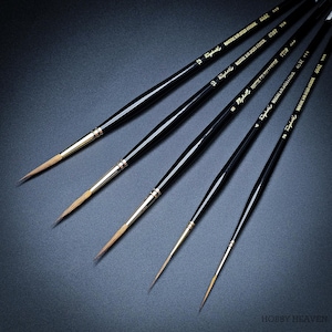 May include: Five black artist paint brushes with gold ferrules and fine tips are displayed diagonally. The brushes, branded "Raphael", vary in size, with the finest tips visible. The image is set against a dark background.