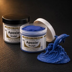 Pode incluir: Dois recipientes de composto de modelagem Aves Apoxie Sculpt, um cinza e outro azul, com uma escultura de golfinho azul. O recipiente azul aberto revela o composto. Os recipientes são rotulados com informações do produto.