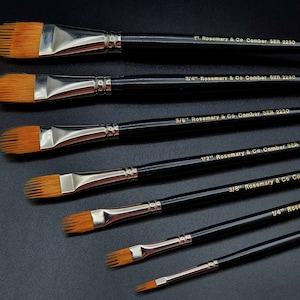 May include: A set of six flat paint brushes with black handles and gold lettering. The brushes are labeled with their size: 1/8", 1/4", 3/8", 1/2", 5/8", and 3/4".