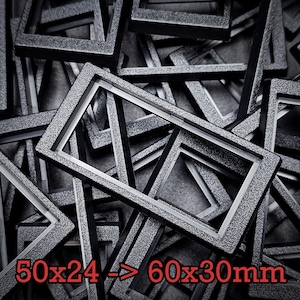 May include: A pile of rectangular frames in dark grey with a textured finish. The frames are of varying sizes, with the text "50x24 -> 60x30mm" in red. The dimensions are in millimeters.