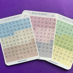 May include: Three sets of colorful number stickers with a boxed design. Each set features numbers 1 through 31 in a grid pattern. The stickers are in shades of blue, pink, and green.
