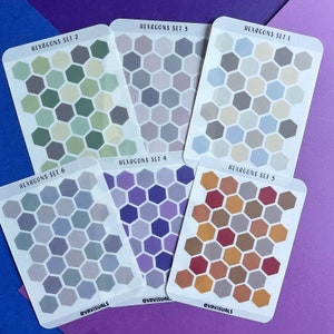 May include: Six sheets of hexagon stickers with different color palettes. Each sheet has the text "Hexagons Set" followed by a number from 1 to 6. The color palettes include shades of green, purple, blue, gray, and orange.