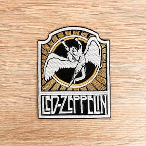 May include: Embroidered patch featuring the Led Zeppelin logo. The patch has a black background with a winged figure inside a gold circle. The band's name, "LED ZEPPELIN," is displayed in white block letters at the bottom, with a white border.