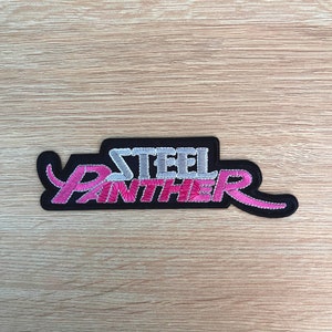 May include: Black embroidered patch with the words "STEEL PANTHER" in pink and silver lettering.
