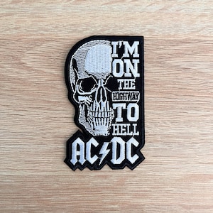 May include: Black and white embroidered patch featuring a skull and the text "I'm on the highway to hell AC/DC".