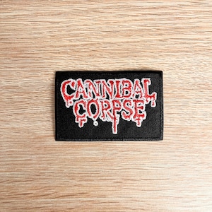 May include: Black embroidered patch with the words "Cannibal Corpse" in red and white lettering. The lettering has a dripping effect.