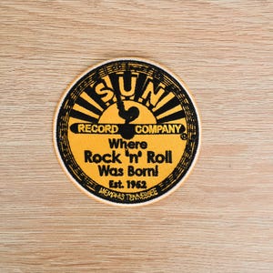 May include: A circular patch with the text "SUN RECORD COMPANY" and "Where Rock 'n' Roll Was Born!" in black and yellow. The patch also includes the text "Est. 1952" and "MEMPHIS TENNESSEE".