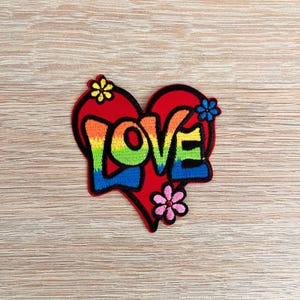 May include: A red heart-shaped patch with the word "LOVE" in rainbow colours and small flower accents.