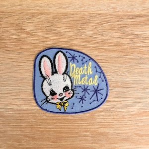 May include: Embroidered patch with a light blue background and a white bunny face with pink ears and a yellow bow tie. The patch reads "Death Metal" in yellow script, with yellow starbursts.