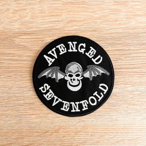 May include: Black and white embroidered patch with the words "Avenged Sevenfold" and a skull with wings.