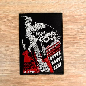 May include: Black embroidered patch with the words "My Chemical Romance" in white script. The patch features a red and white graphic design and the text "One Night Only". The patch is rectangular.