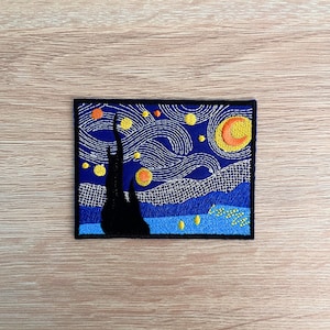 May include: An embroidered patch depicting a blue and white starry night sky with a yellow crescent moon and a black silhouette of a tree. The patch is ideal for adding a touch of art to clothing, bags, or other accessories.