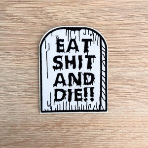 Peut inclure: Un écusson blanc avec une bordure noire, en forme de pierre tombale. L'écusson porte l'inscription "EAT SHIT AND DIE!!" en lettres noires grasses avec un effet dégoulinant, ce qui lui donne un aspect effrayant. L'écusson est probablement à repasser ou à coudre.