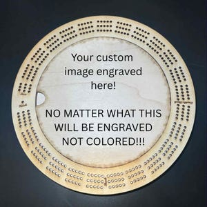 May include: A round wooden cribbage board with engraved holes and text. The center of the board has the text "Your custom image engraved here!" and "NO MATTER WHAT THIS WILL BE ENGRAVED NOT COLORED!!!"