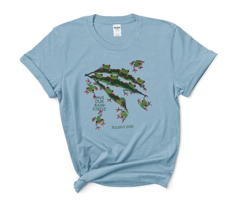 Op de afbeelding: Lichtblauw T-shirt met een afbeelding van groene boomkikkers op een tak. De tekst "Save Our Rainforest" en "Toledo Zoo" staan op het shirt gedrukt.