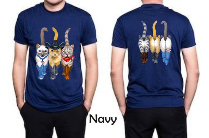 May include: A navy blue t-shirt with a graphic of four cats wearing cowboy hats and boots. The cats are walking in a line, with the cat in the front wearing a sheriff's star. The back of the shirt features the same graphic, but the cats are facing away from the viewer.