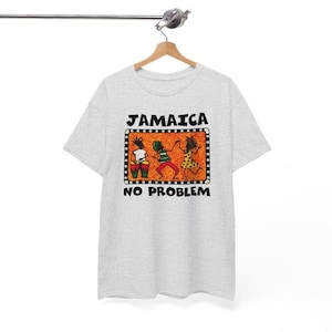 以下が含まれることがあります： 「JAMAICA NO PROBLEM」の黒い文字が入ったライトグレーのTシャツ。3人の人物が踊ったりドラムを演奏したりするカラフルなグラフィックが特徴です。グラフィックは点線で囲まれています。