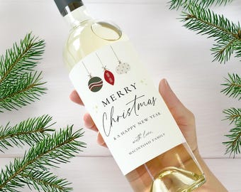 May include: A bottle of white wine with a festive Christmas label. The label reads "Merry Christmas & A Happy New Year" with decorative ornaments. Green pine branches frame the bottle, creating a holiday theme.