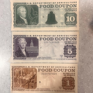 May include: Three vintage U.S. Department of Agriculture Food Coupons. The denominations are $1, $5, and $10. Each coupon features a portrait of a historical figure and the Liberty Bell. The $10 coupon features Alexander Hamilton.