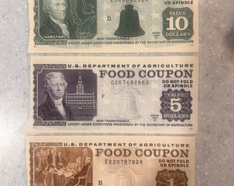 May include: Three vintage U.S. Department of Agriculture Food Coupons. The denominations are $1, $5, and $10. Each coupon features a portrait of a historical figure and the Liberty Bell. The $10 coupon features Alexander Hamilton.