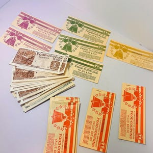 May include: Assortment of vintage U.S. Department of Agriculture food coupons in various colors. Coupons feature a Liberty Bell graphic and text indicating values of $1.00, $2.00, $7.00, $40.00, and $65.00. Some coupons are stacked.