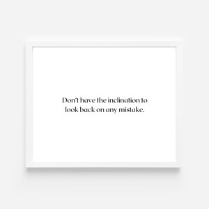 May include: A framed print with a white border. The print features the text "Don't have the inclination to look back on any mistake" in a simple, elegant font. The background is plain white.