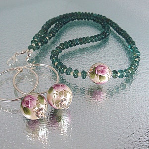 Pu&ograve; includere: Un set di orecchini a cerchio d'argento con perline a motivi floreali e una collana abbinata con perline verdi. La collana ha una perlina pi&ugrave; grande a motivi floreali al centro.