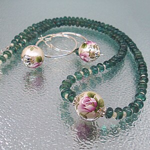 Pu&ograve; includere: Una collana di pietre preziose verdi con perline a motivi floreali e orecchini abbinati. La collana e gli orecchini sono realizzati in argento.