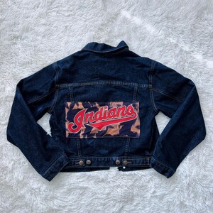 May include: A dark blue denim jacket with a patch on the back that says "Indians" in red and white lettering on a brown and white background.
