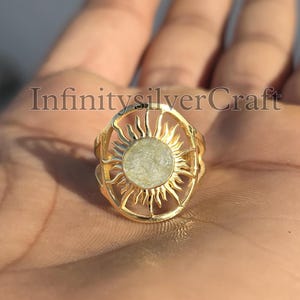 Puede incluir: Anillo de oro con un diseño de sol. El sol tiene una piedra blanca en el centro.
