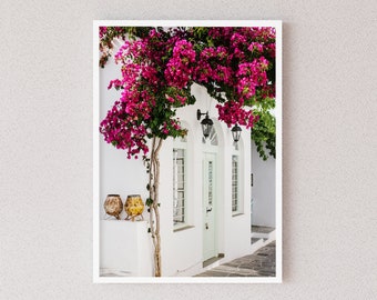Könnte beinhalten: Ein weißes Gebäude mit einer grünen Tür und einem rosafarbenen Bougainvillea-Ranken, der darüber wächst. Zwei Terrakotta-Töpfe stehen vor dem Gebäude auf dem Boden.