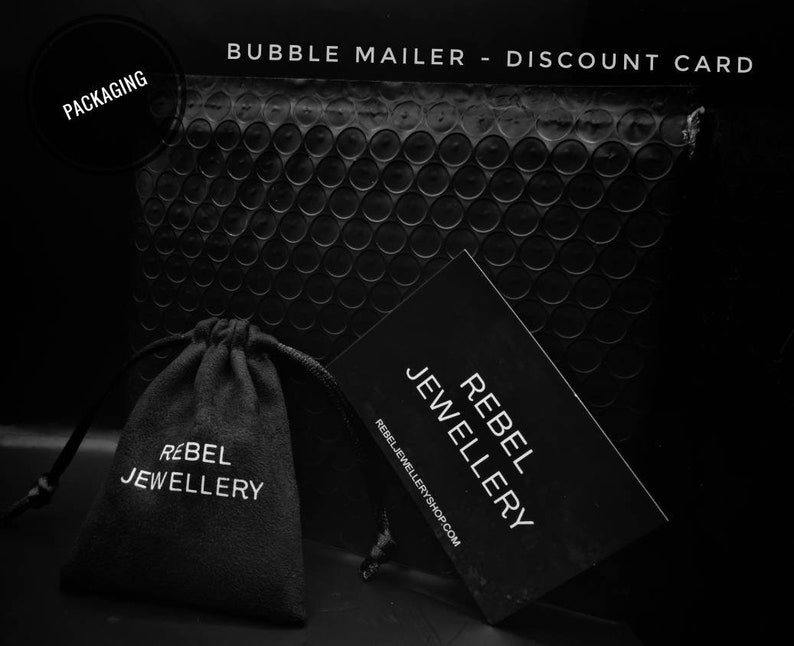 May include: Black bubble mailer with a black velvet pouch and a black discount card. The pouch and card both have white text that reads 'Rebel Jewellery' and the discount card also includes the website 'rebeljewelleryshop.com'.