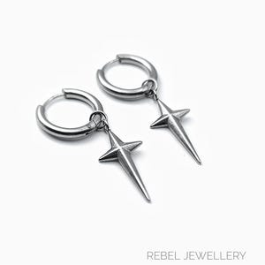 May include: A pair of silver-colored hoop earrings with star-shaped pendants. The earrings are made of a shiny metal and hang from the hoops. The text "REBEL JEWELLERY" is at the bottom of the image.