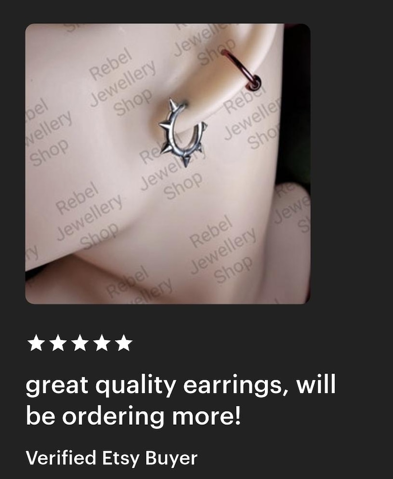 May include: A silver hoop earring with spike details is shown on an ear. A smaller, dark red hoop earring is also visible. The text "great quality earrings, will be ordering more!" is displayed below the earrings.
