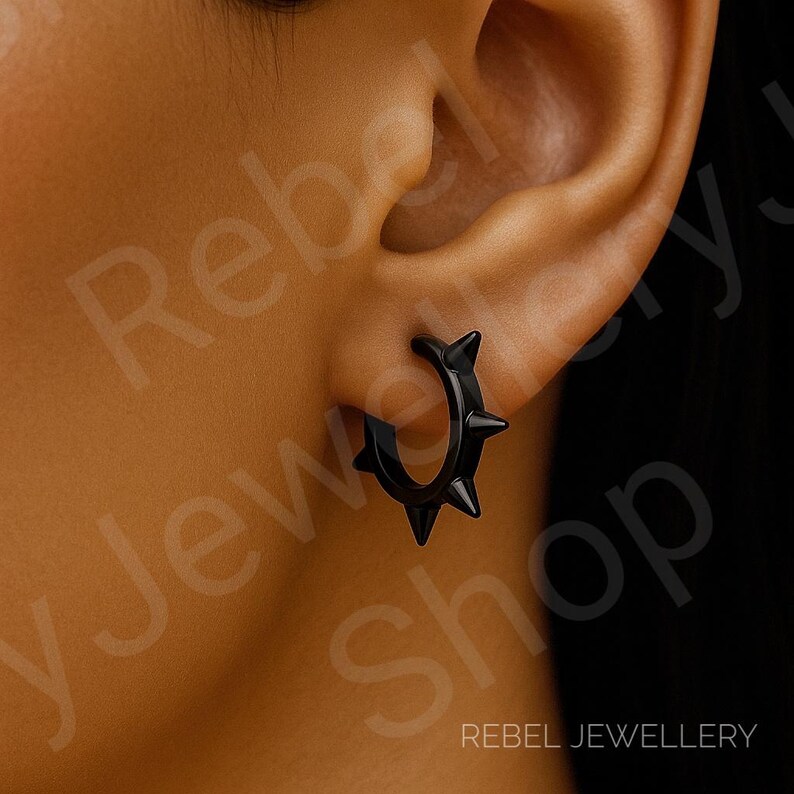 May include: A black hoop earring featuring a series of sharp, pointed spikes along the outer edge. The earring is circular in shape with a smooth, glossy finish, designed to be worn through the earlobe as a singular piece of jewelry.