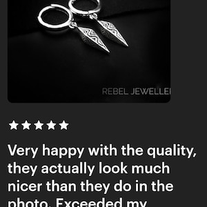 May include: Silver hoop earrings with dangling, pointed pendants. The pendants have a detailed, geometric design. The earrings are displayed on a dark background. The text "REBEL JEWELLEI" is visible.