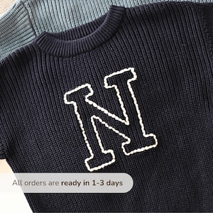 Puede incluir: Jersey de punto azul marino con una gran "N" blanca bordada en la parte delantera. El jersey tiene cuello redondo y mangas cortas. El texto "All orders are ready in 1-3 days" está en la parte inferior de la imagen.