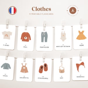May include: A set of 14 printable flashcards featuring illustrations of different clothing items in French. The flashcards include words like "T-shirt", "Pull", "Pantalon", "Maillot de Bain", "Robe", "Veste", "Salopette", "Chaussures", "Sac", and "Bandeau".