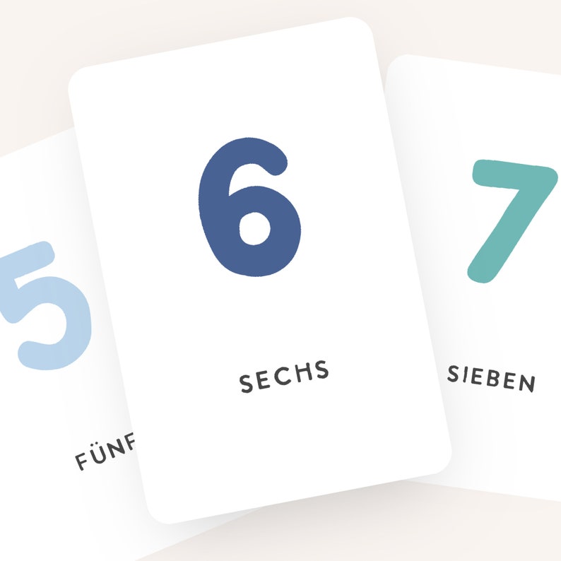 May include: Three white cards with blue, green, and light blue numbers on them. The numbers are 5, 6, and 7. The words "F&uuml;nf", "Sechs", and "Sieben" are written below the numbers.